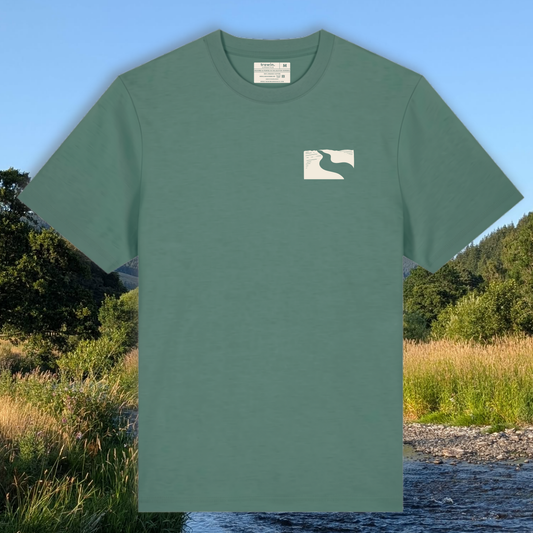 A sage green short-sleeve crewneck t-shirt with a small white graphic on the left chest, displayed against a scenic background of a river and forest.
